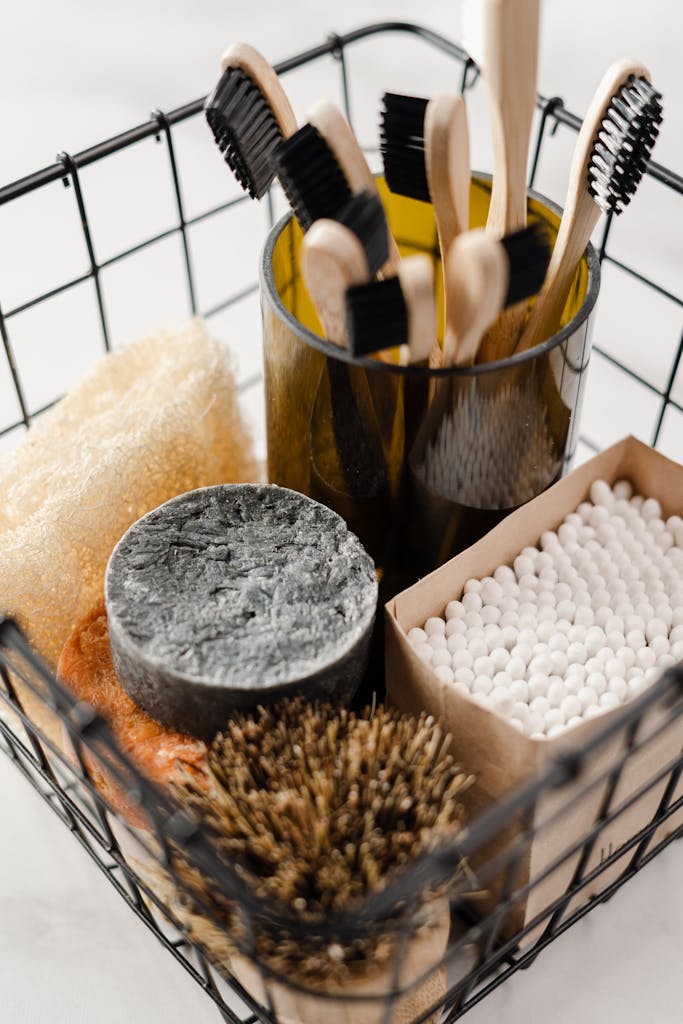 Collection of eco-friendly bathroom essentials including toothbrushes and cotton buds in a wire basket.